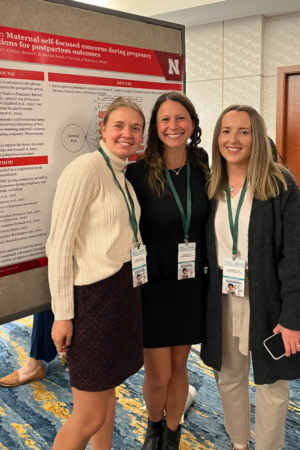 Graduate students Frannie, Lauren, and Rachel standing in front of a poster