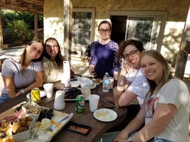 Five members of the Family Development Lab smile for a photo as they sit at a picnic table